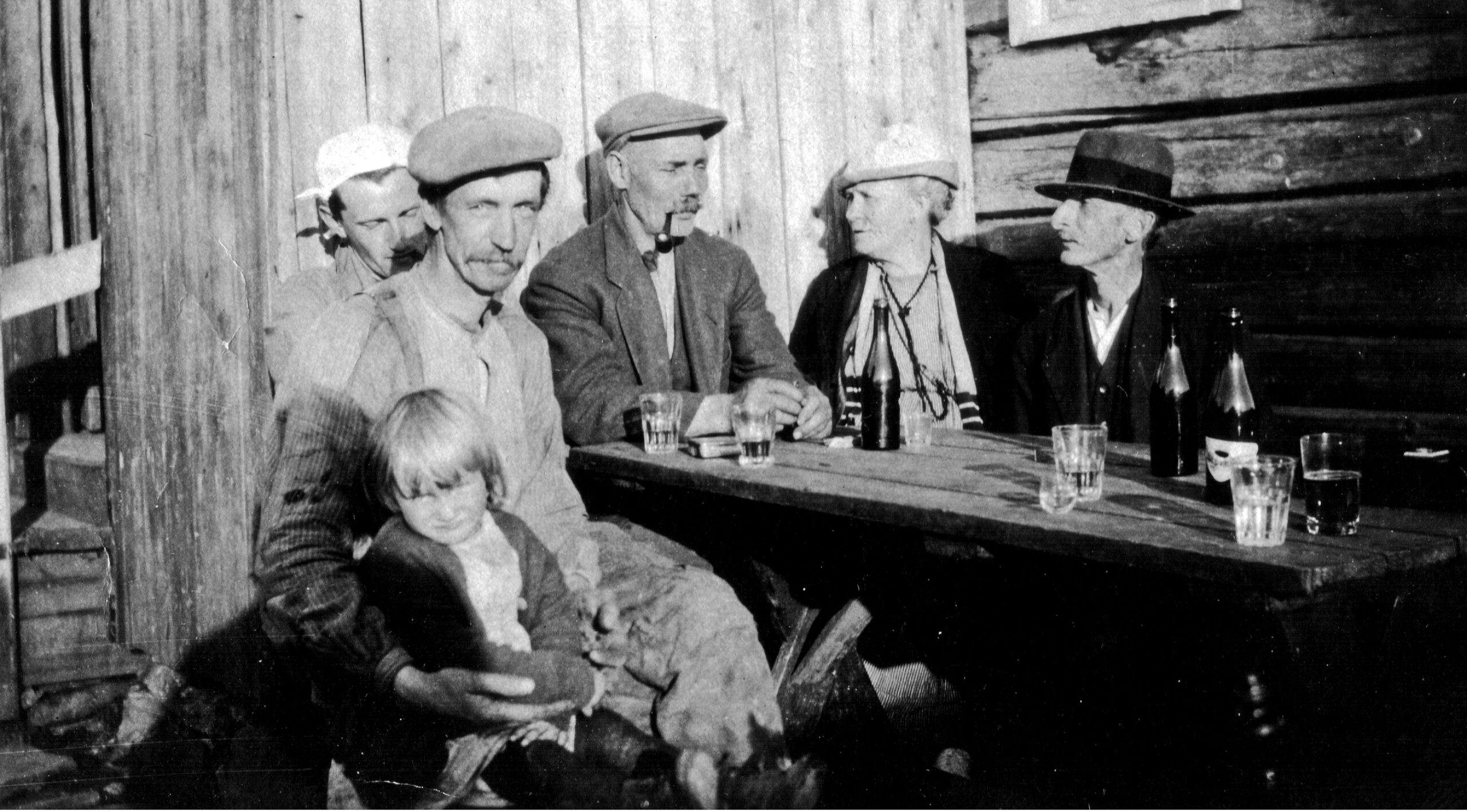 Bildet er tatt på Skytten sommeren 1922. Hans Amundsen sitter til venstre med datteren på fanget. Kona (med hodetørkle) sitter bak. De tre andre personene er ukjente. Kanskje det er «Mariholten» som tar bildet? Det står seks glass på bordet, men bare fem voksne personer sees. Bildet lå blant «Mariholten»s eiendeler. Amundsen med familie flyttet til Sarabråten og bodde der i mange år. Etter annen verdenskrig flyttet de til Oppsal.