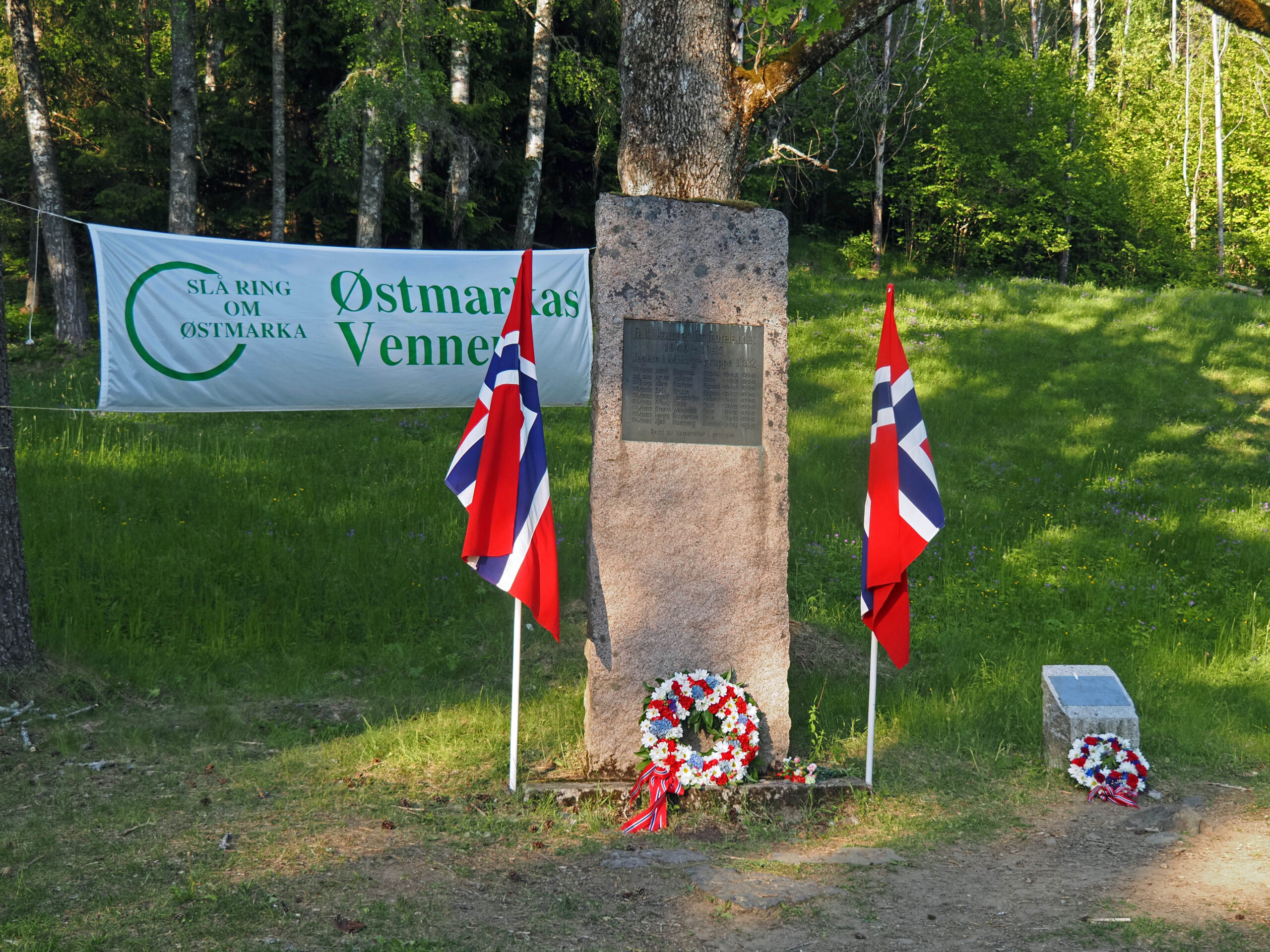 Milorg-bautaen og en minneplakett står ved siden av skogsveien fra Østmarksetra mot Mariholtet og Rustadsaga. Kransene ble nedlagt under årets arrangement.