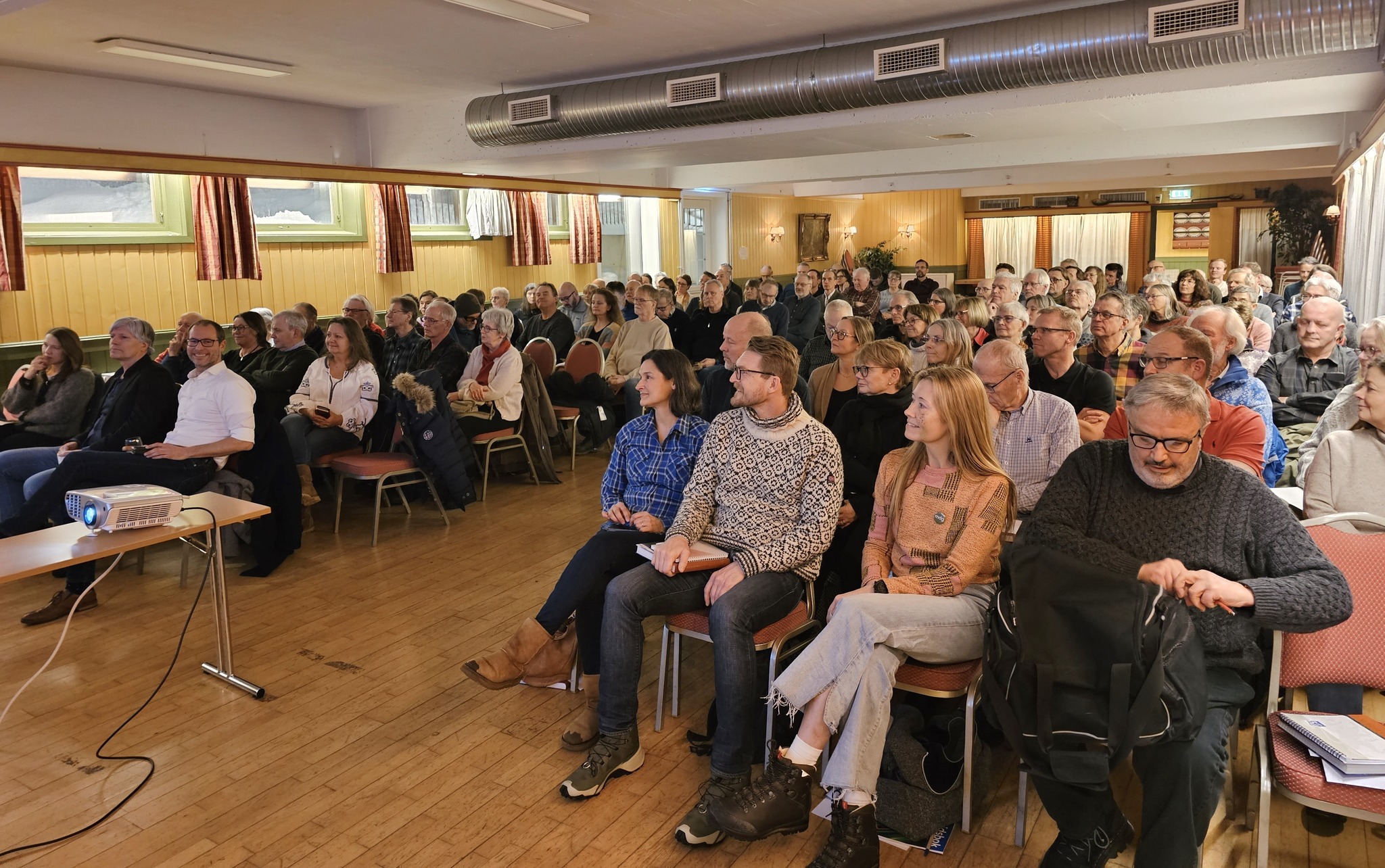 Fullsatt sal på Skullerudstua med ca. 150 frammøtte. På første rad satt Une Bastholm, Ola Elvestuen og Fredrik Holth på den ene siden av midtgangen. På den andre siden satt politikere fra Lørenskog: Anita Patel, Dan Levi Hykkerud, Lisa Kara Frøyland og Bjørn Bakke. Foto: Steinar Saghaug.