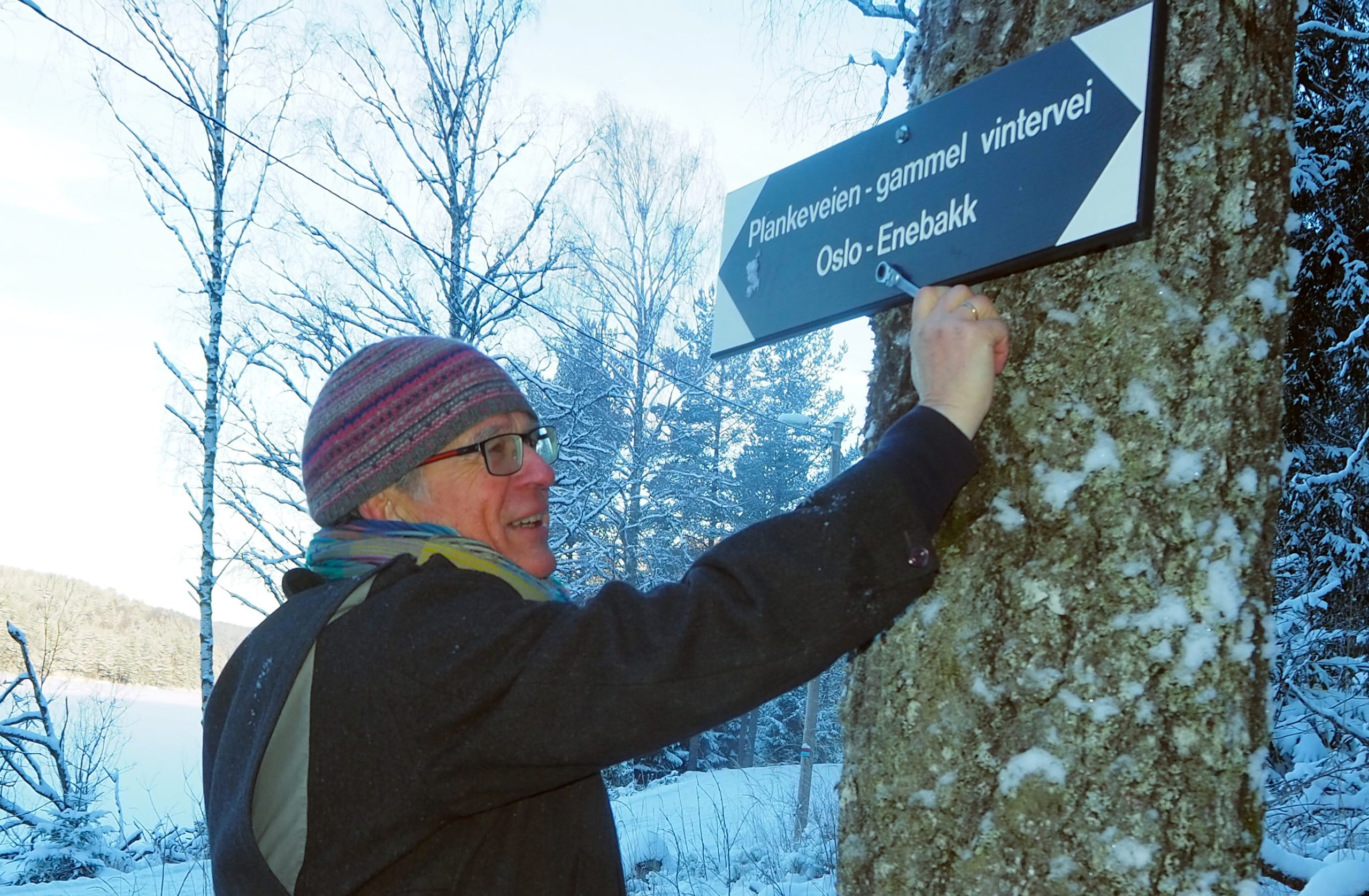 Lars skrudde opp det aller første av de nye Plankeveien-skiltene en bitende kald desemberdag i 2022, mens kameratene i dugnadsgjengen sto andektige rundt ham. Foto: Bjarne Røsjø.